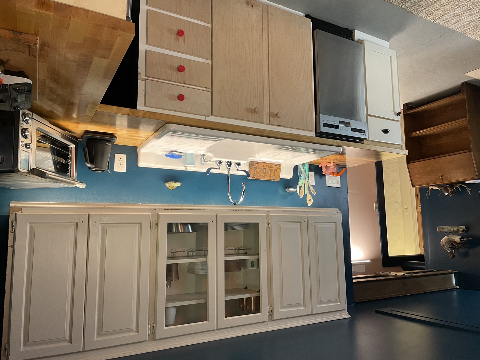 Full kitchen with upper and lower cabinets, range hood, and blue tile backsplash
