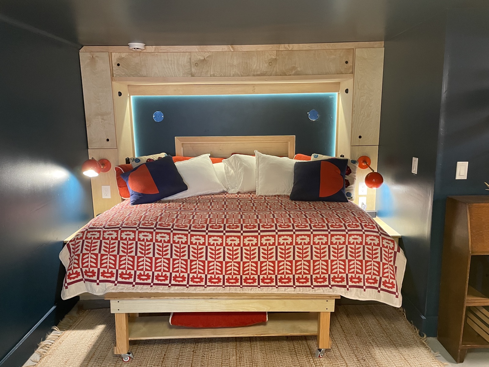 Queen Murphy bed made up as a day bed with dramatic blue walls and warm accent lighting