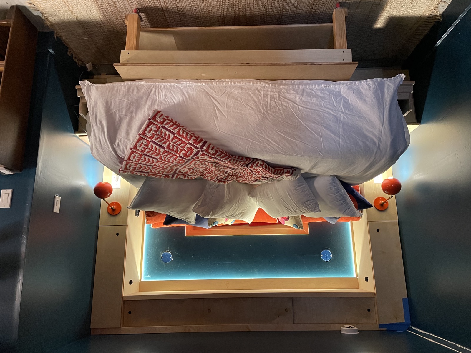 Queen Murphy bed made up with patterned quilt and reading lights