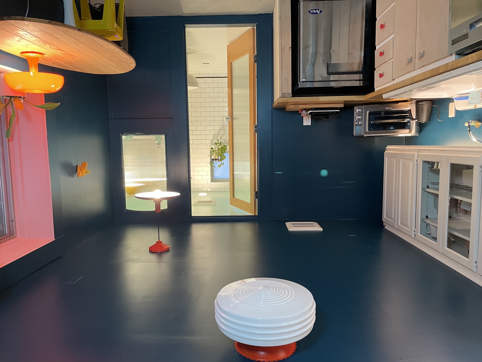 Living area with vintage pendant lamp, blue walls, and open bathroom door